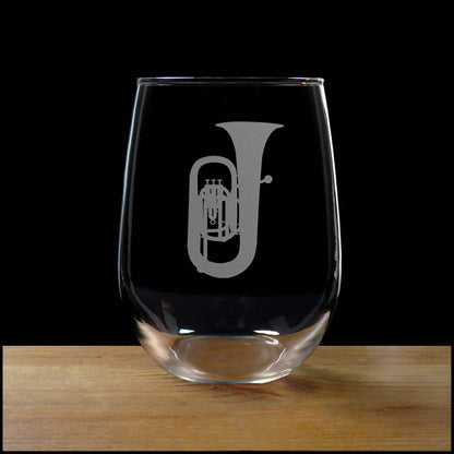 Stemless wine glass with etched Tuba Design on a wood surface with a black background