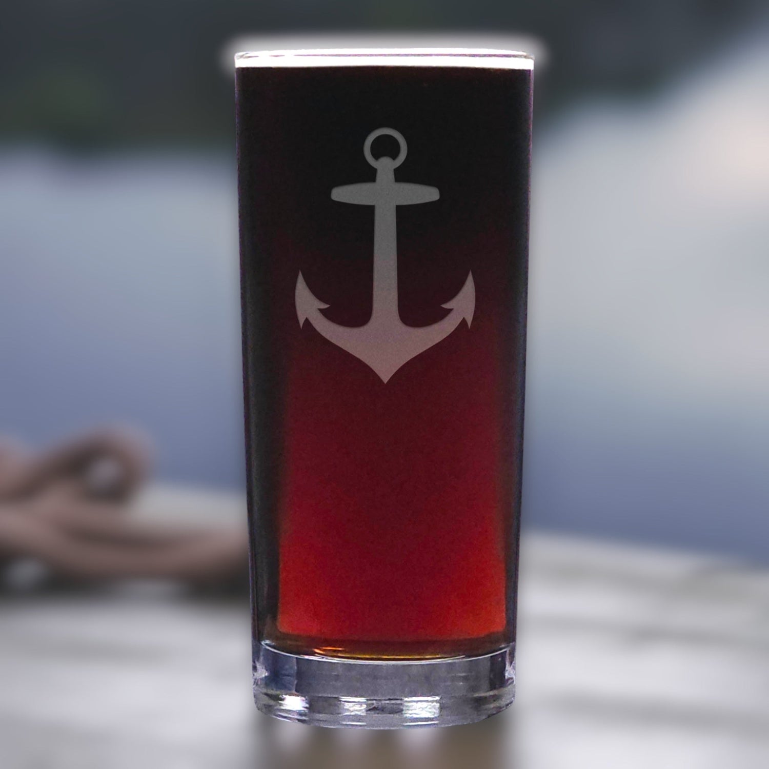 Glass with an anchor design filled with a red liquid on a blurred background