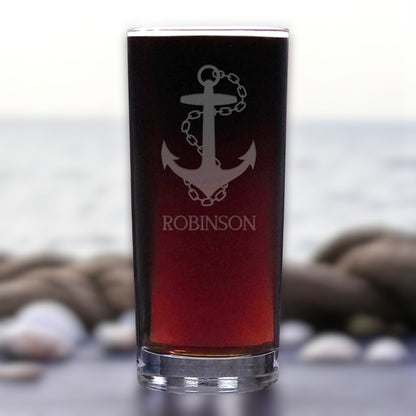 Glass with anchor design and 'ROBINSON' text against a blurred natural background