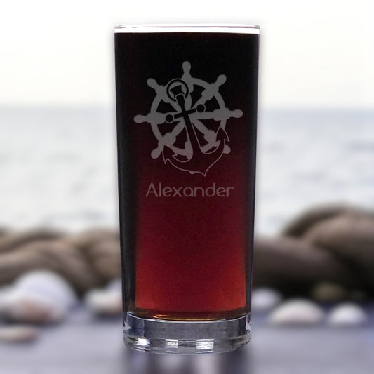 Glass with engraved design and 'Alexander' text against a blurred natural background