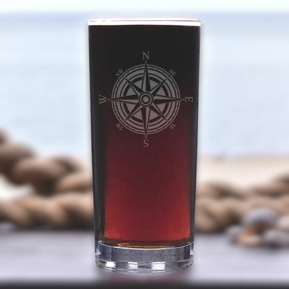 Black glass with compass design filled with red liquid on a blurred natural background