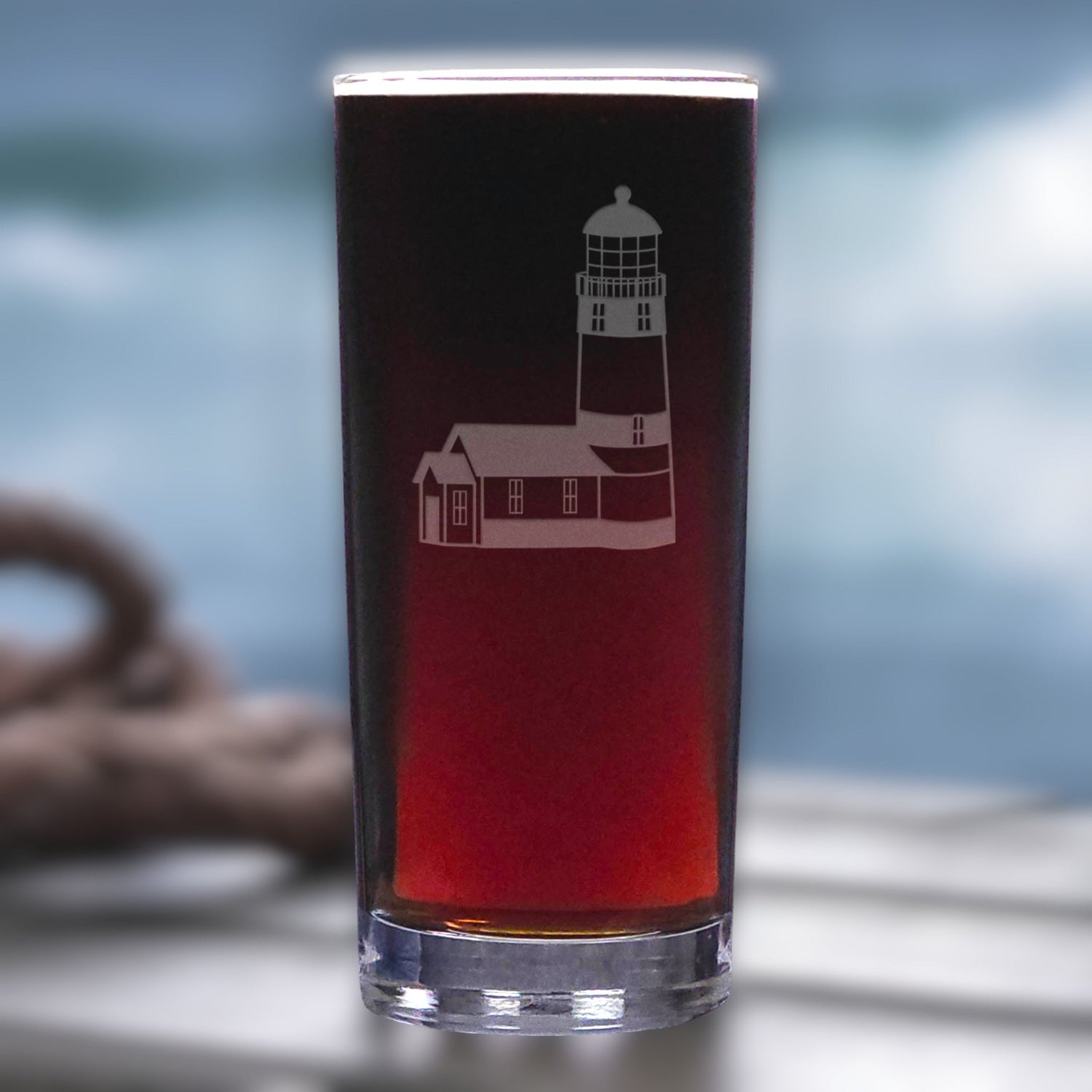 Pint glass with a lighthouse design filled with red liquid on a blurred background