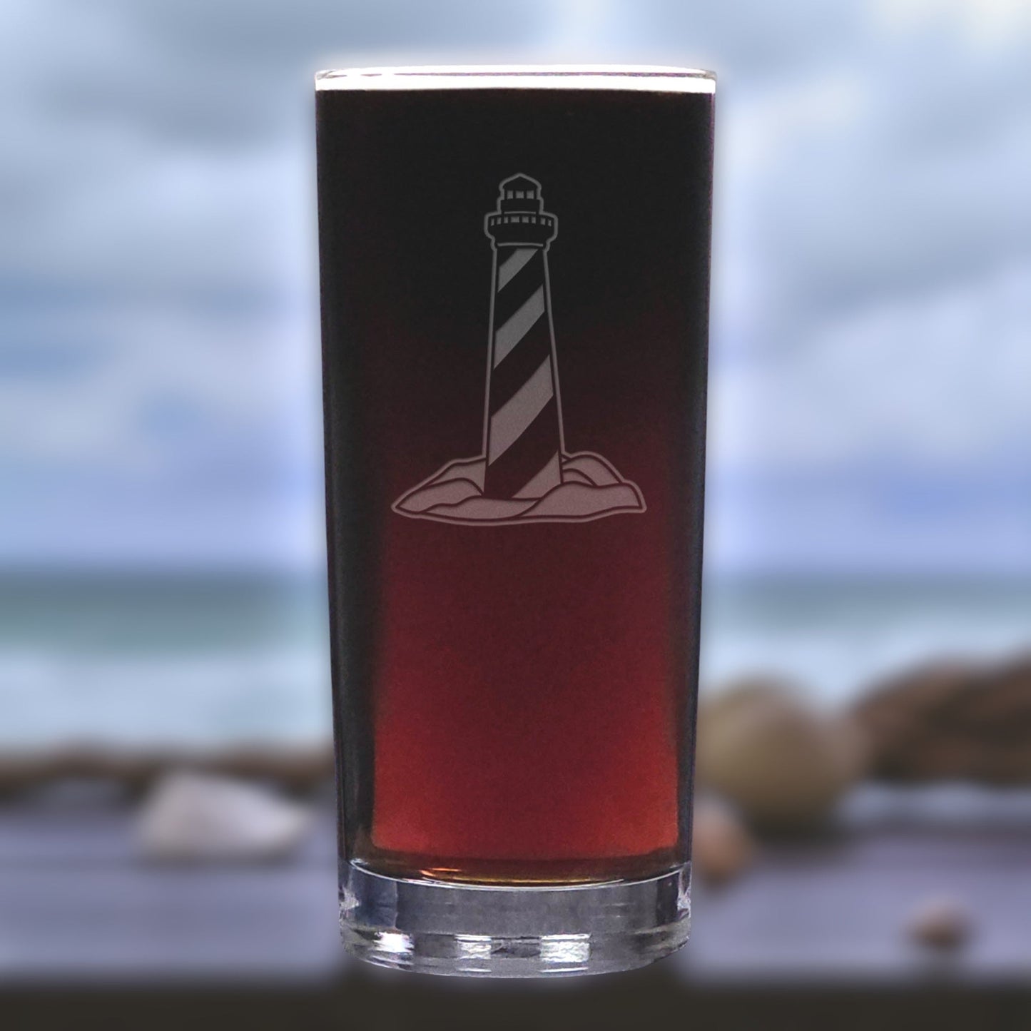 Glass with lighthouse design on a blurred beach background