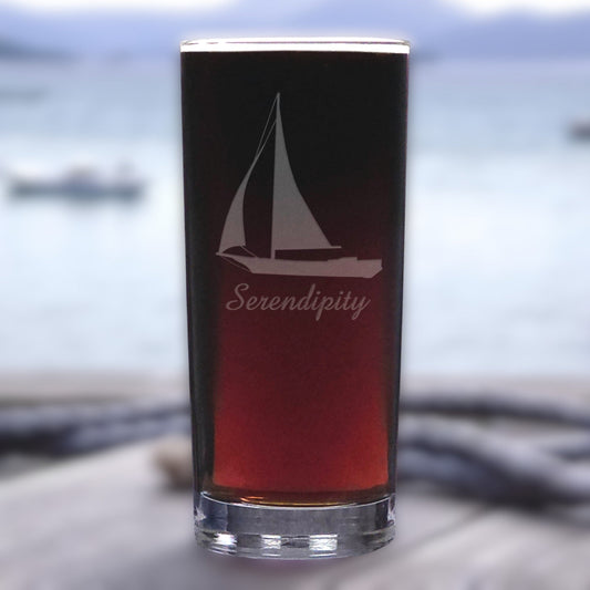Glass with sailboat design and 'Serendipity' text against a blurred water background