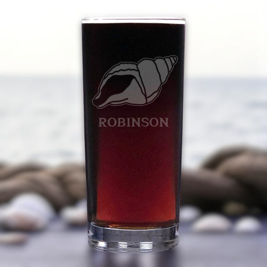 Glass with a shell design and 'ROBINSON' text against a blurred natural background
