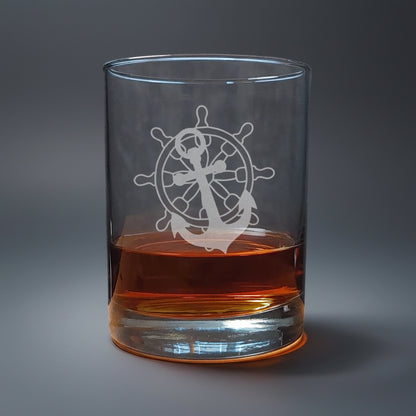 Clear glass with ship's wheel and anchor design, filled with amber liquid 