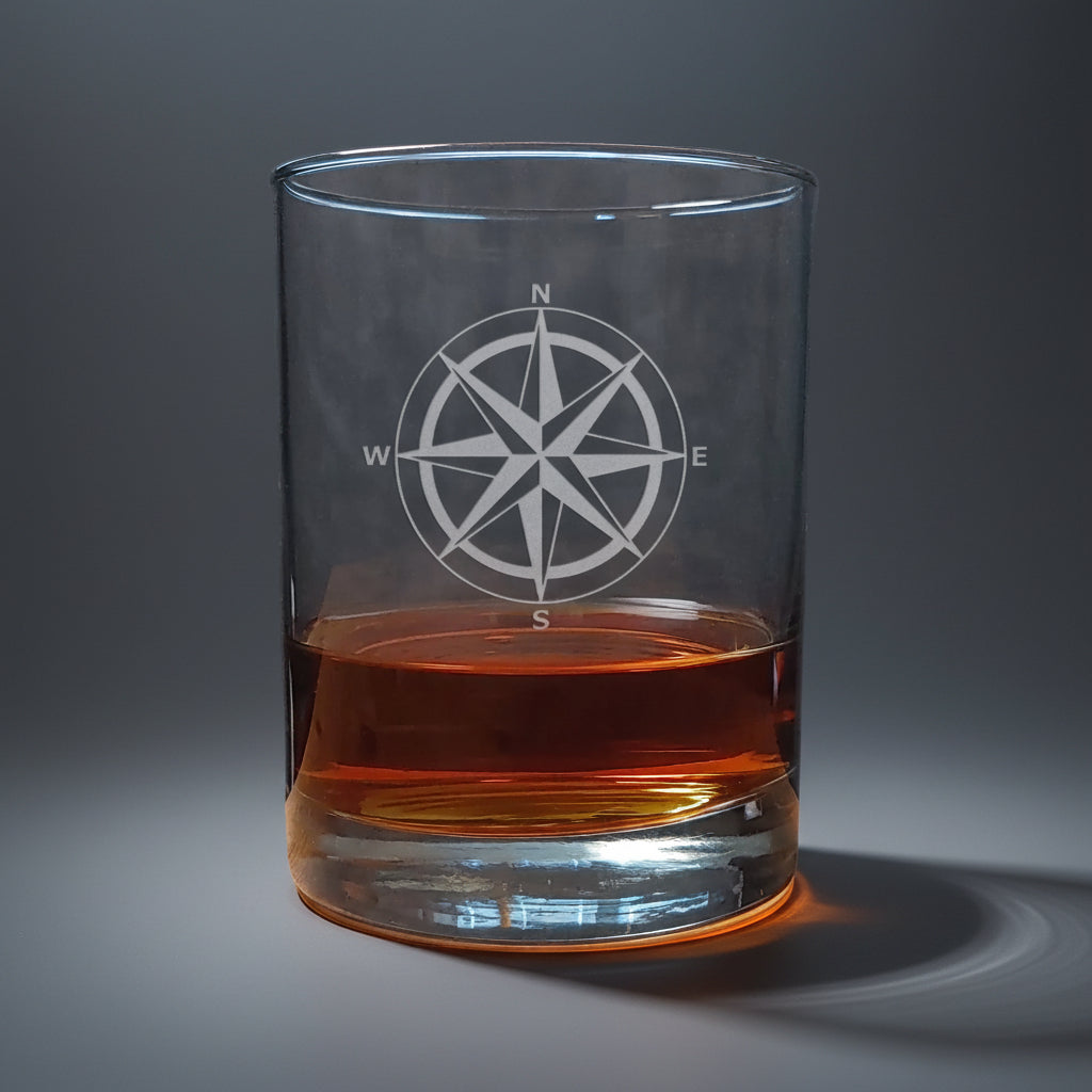 Clear glass with a compass design filled with amber liquid 