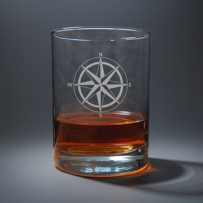 Clear glass with a compass design filled with amber liquid 