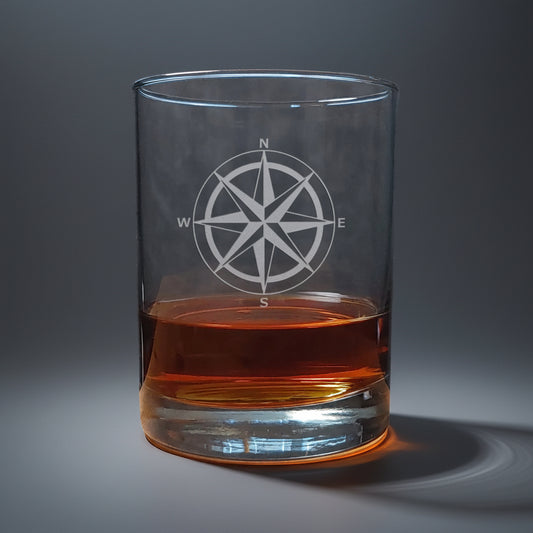 Clear glass with a compass design filled with amber liquid 