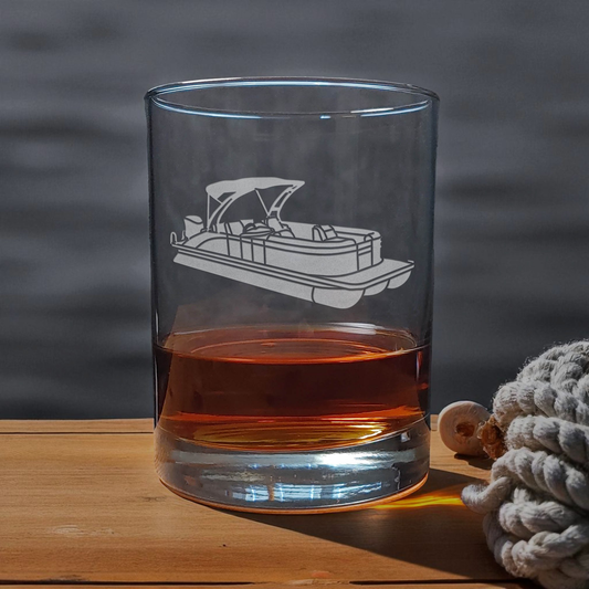 Clear glass with pontoon boat etching on a wooden surface with a blurred water background