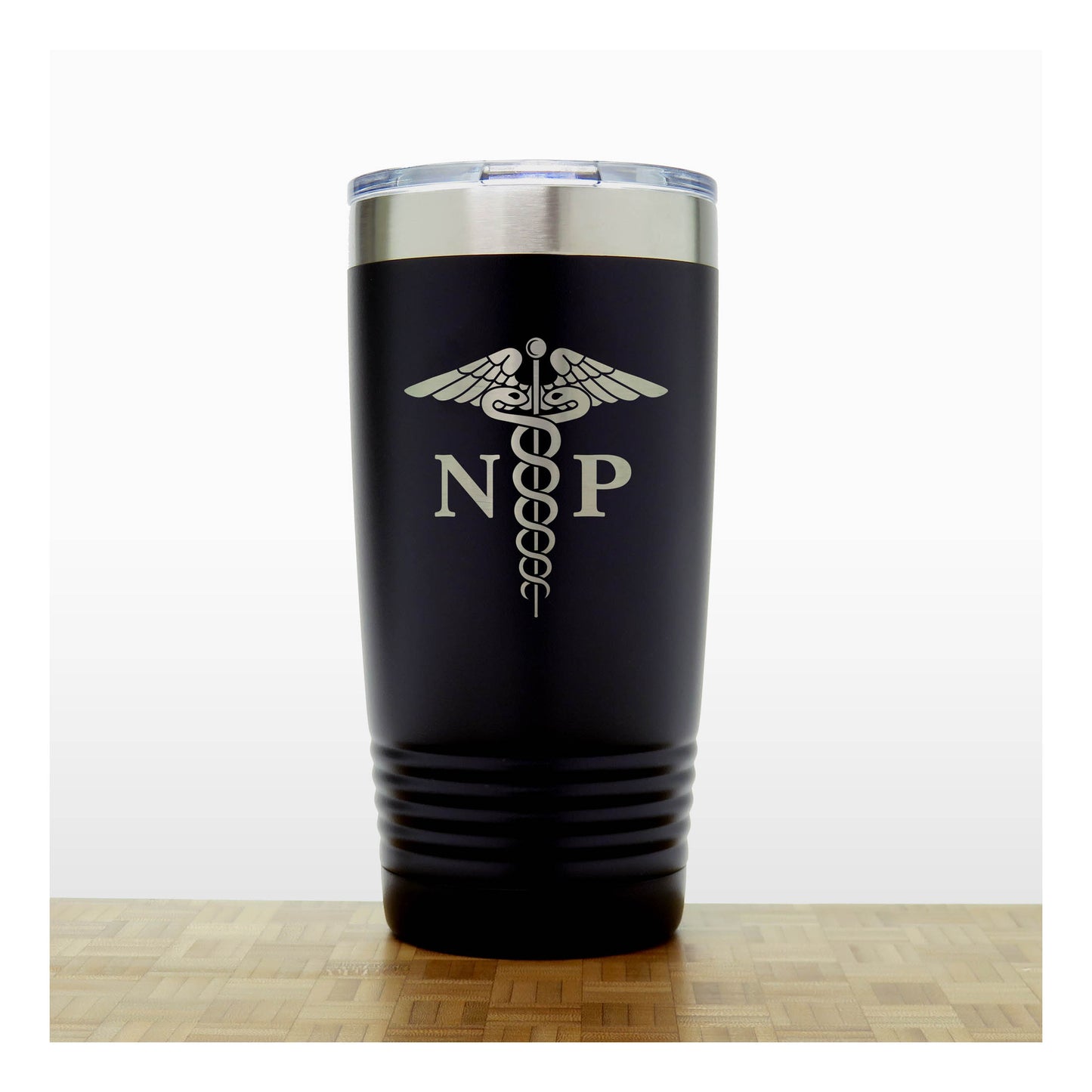 A black insulated travel tumbler with a stainless steel lid, With an laser engraved  medical caduceus symbol with the letters 'NP' on the front, standing on a wooden surface against a white background.