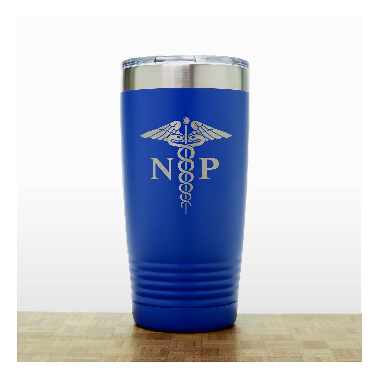 A royal blue insulated travel tumbler with a stainless steel lid, With an laser engraved  medical caduceus symbol with the letters 'NP' on the front, standing on a wooden surface against a white background.