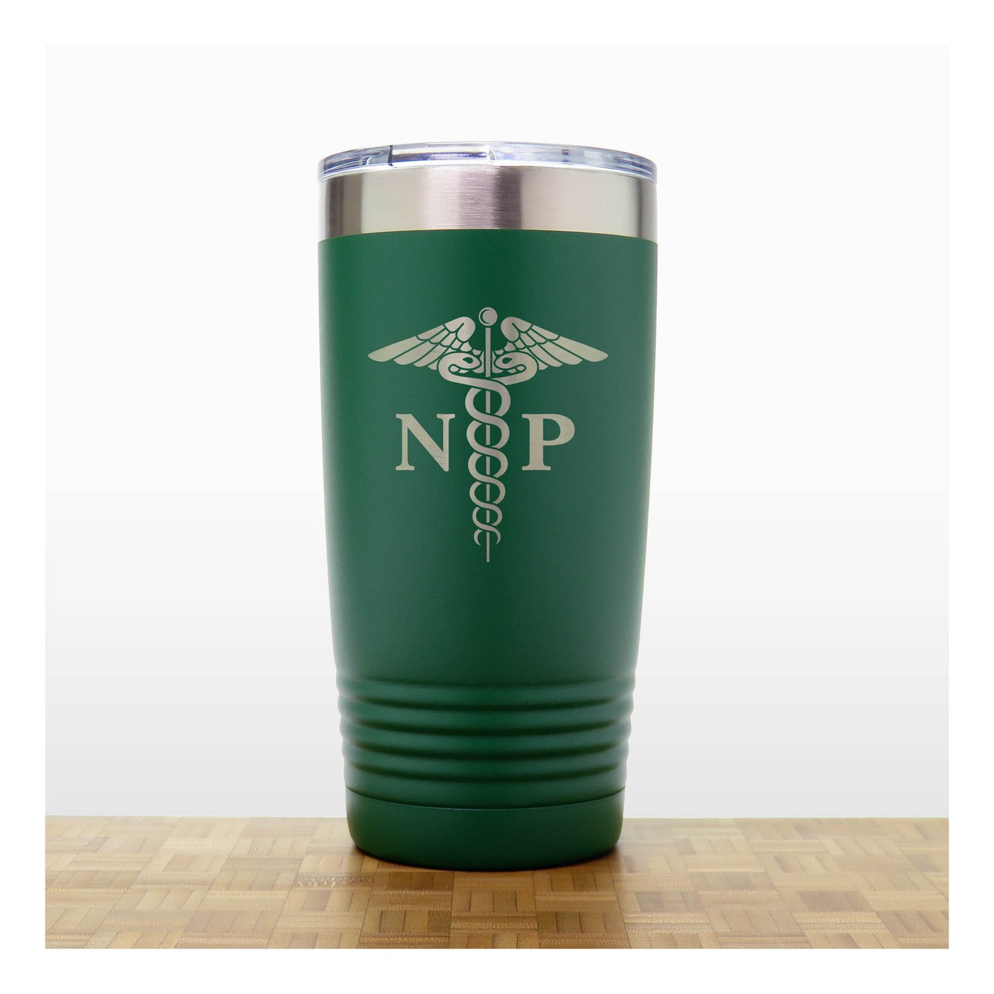 A dark green insulated travel tumbler with a stainless steel lid, With an laser engraved  medical caduceus symbol with the letters 'NP' on the front. The tumbler is shown standing on a wooden surface against a white background.