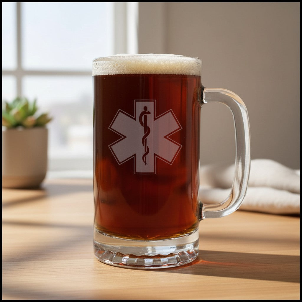 A clear glass beer mug filled with amber beer and topped with white foam, standing on a wooden table. The mug has a EMS Star of Life with a snake wrapped around a rod of Asclepius.