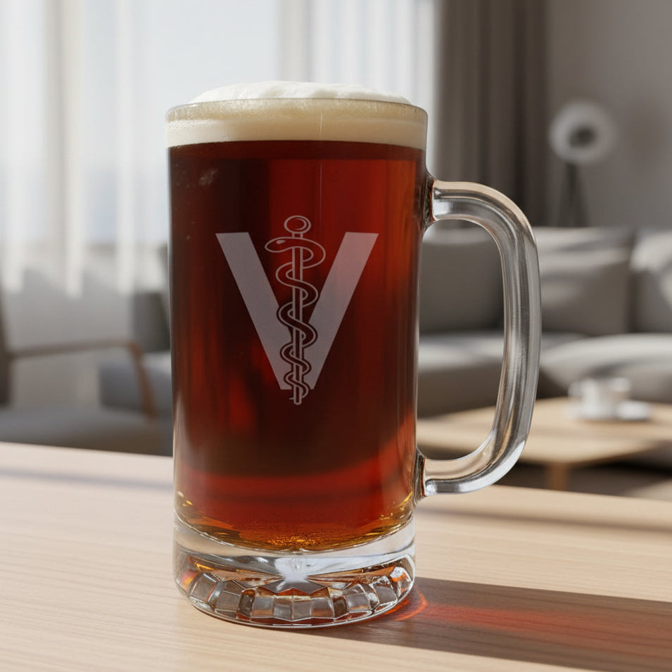 A clear glass beer mug with a handle, filled with dark amber beer and topped with white foam,featuring a Veterinarian Symbol comprising of a "V", there is a rod in the middle with a snake wrapped around it , set on a wooden surface with  a living room in the background