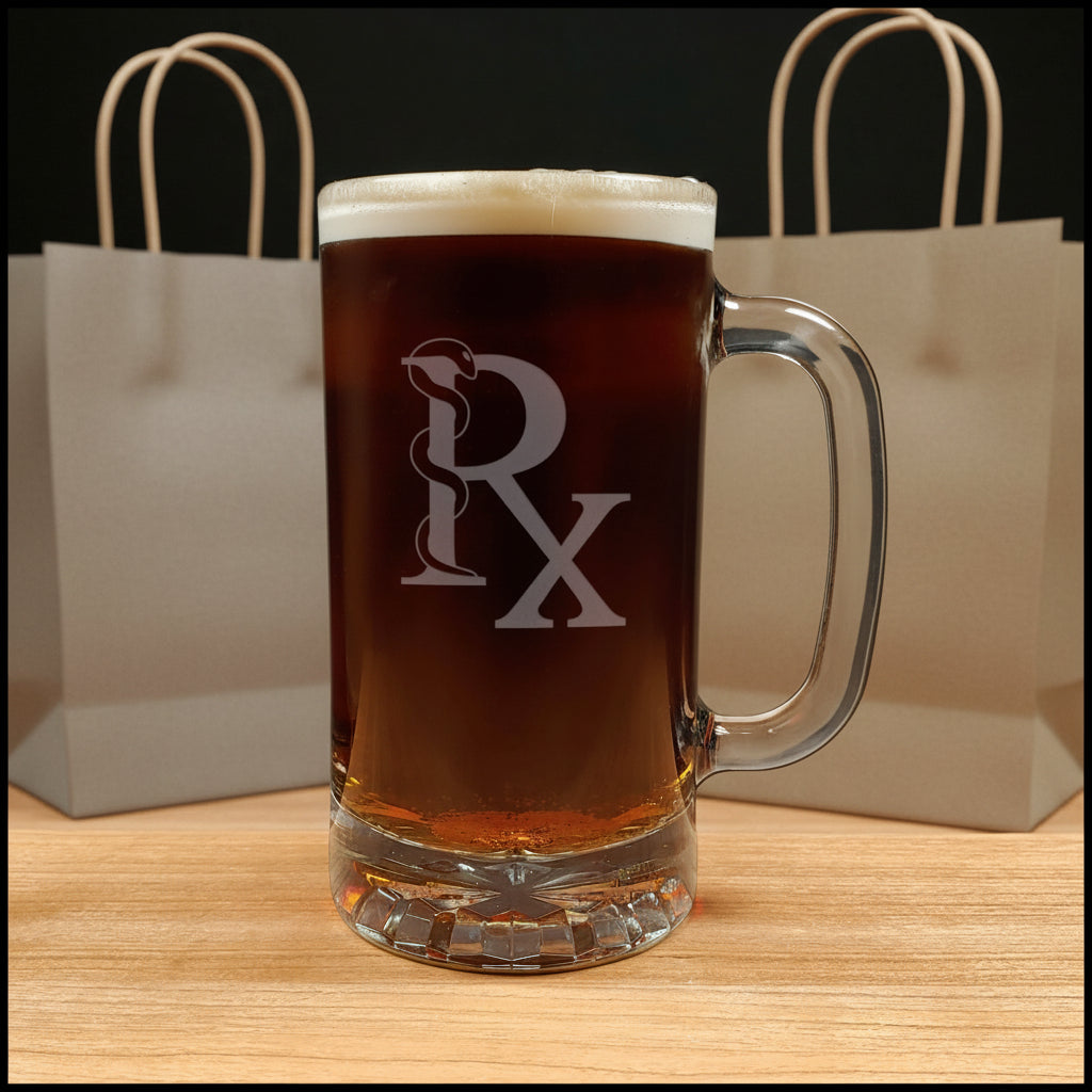 A clear glass beer mug filled with dark amber beer and topped with white foam, featuring an etched Rx symbol on the front, set on a light wood surface.