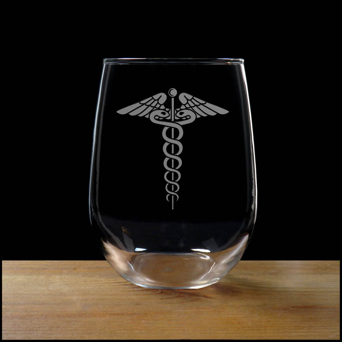 Clear glass with a caduceus symbol on a wooden surface and black background