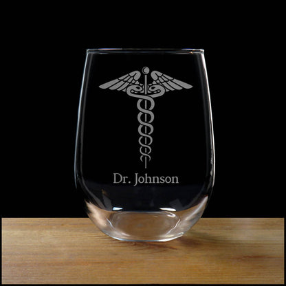 Clear glass with engraved caduceus symbol and 'Dr. Johnson' text on a wooden surface with black background