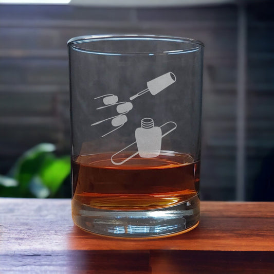 13oz Whiskey Glass with an etched image of finger nails, and a bottle of nail polish and emery board