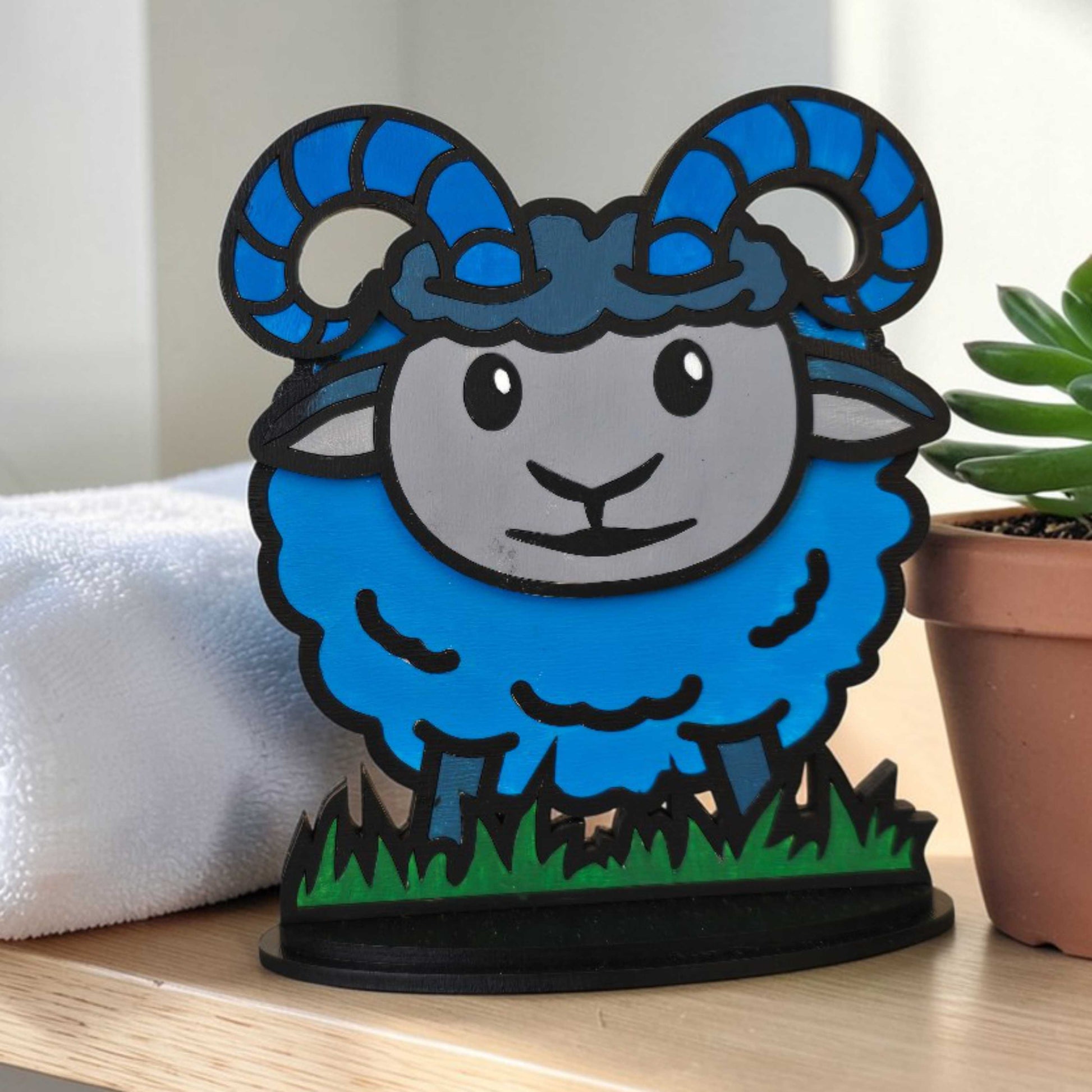 Completed blue ram DIY paintable kit  on a wooden surface with a plant in the background