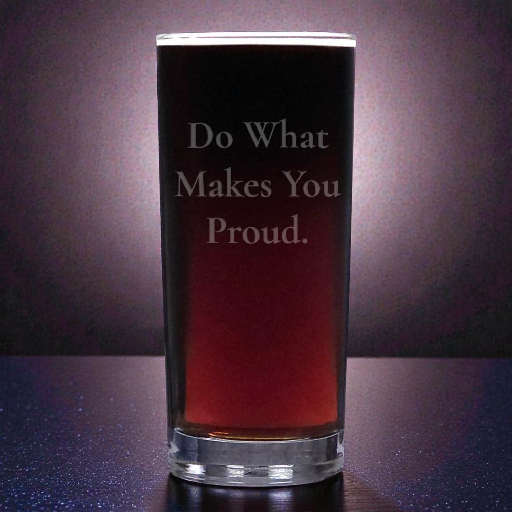 Glass of dark liquid with 'Do What Makes You Proud.' text on a reflective surface.