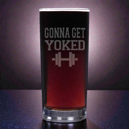 Pint glass with 'Gonna Get Yoked' text and barbell graphic on a dark background