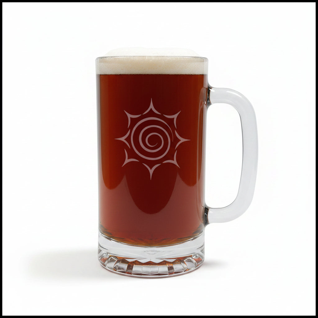 A clear glass beer mug with a handle, filled with dark amber beer and topped with white foam, featuring a etched spiral sunburst design on the front, set on a light wood surface against a white background.