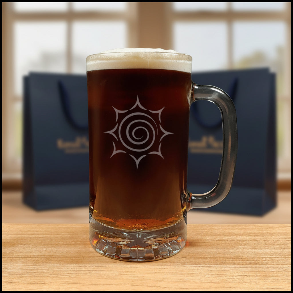 A clear glass beer mug with a handle, filled with dark amber beer and topped with white foam, featuring a etched spiral sunburst design on the front.