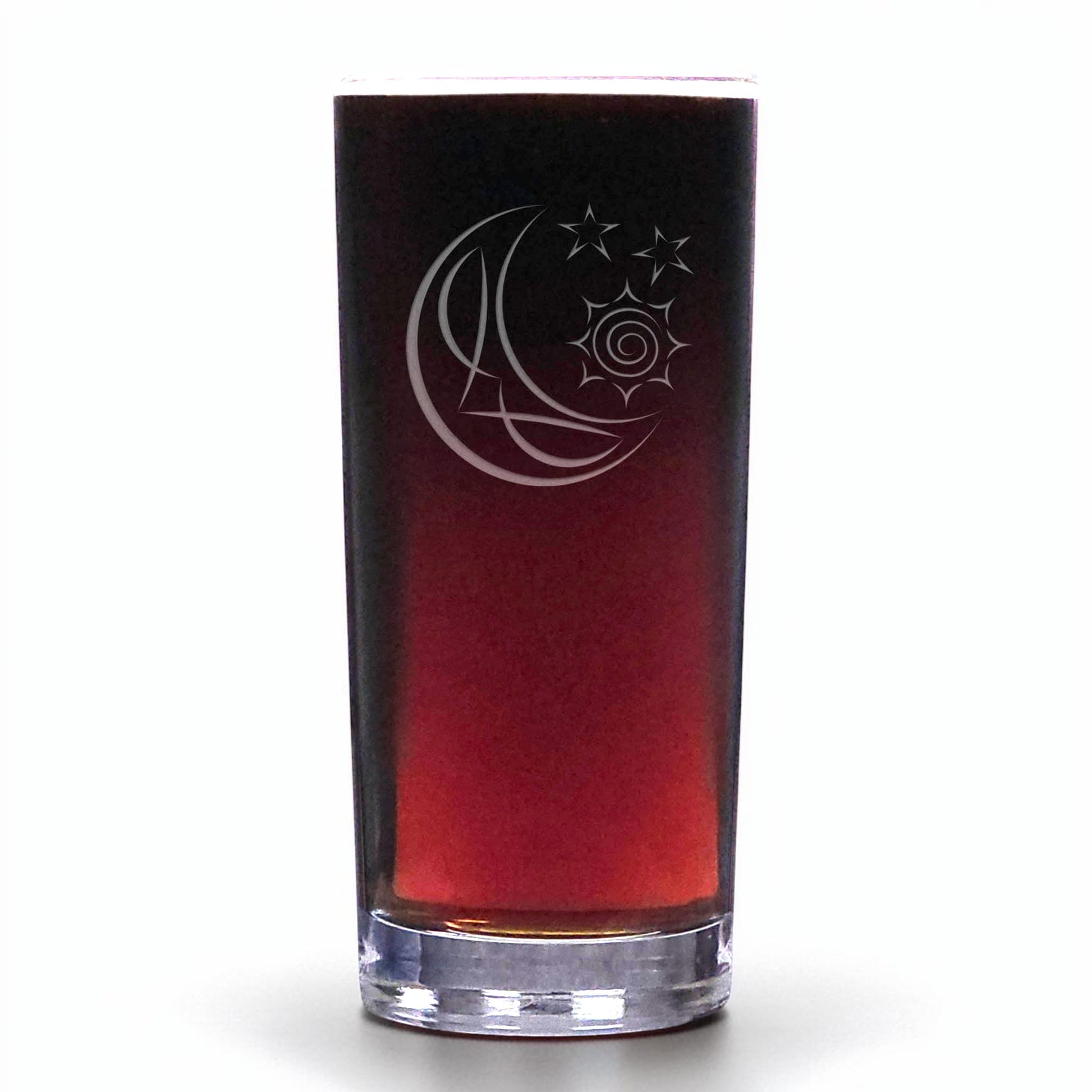 A clear glass shot glass with a gradient tint from dark brown to deep red, featuring an etched crescent moon, sun, and stars design on the front, set against a plain white background.