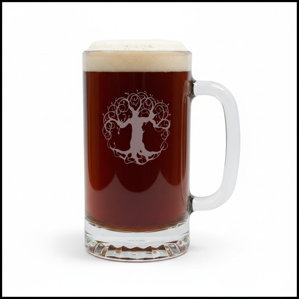 A clear glass beer mug filled with dark amber beer and topped with white foam, featuring an etched tree-of-life logo on the front, set against a plain white background.