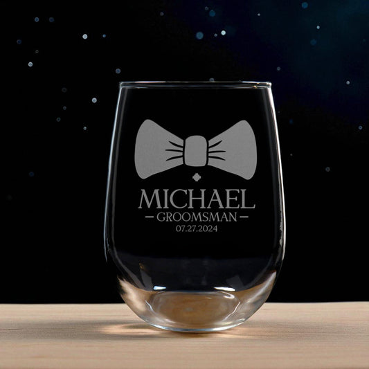 Clear glass wine glass with engraved bow tie design and text on a dark background