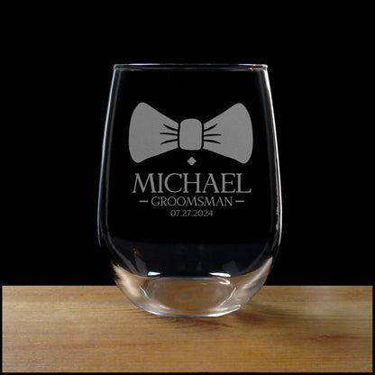 Clear glass with bow tie design and engraved text on a wooden surface with black background