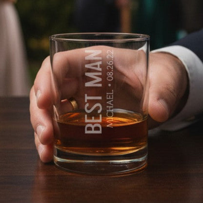 Hand holding a glass of whiskey with 'Best Man' text at a wedding reception.