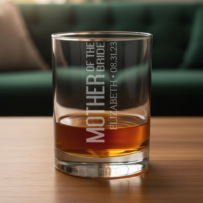 Glass tumbler with engraved text on a wooden surface with a green couch in the background