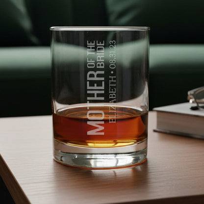 Glass of whiskey with engraved text on a wooden table, blurred green sofa in the background