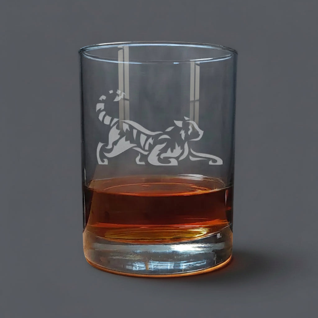 Clear glass with a tiger etching filled with amber liquid on a grey lit background