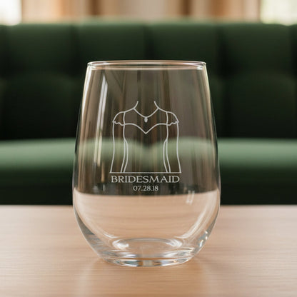 Clear glass with engraved design of a wedding dress and text with a green couch in the background
