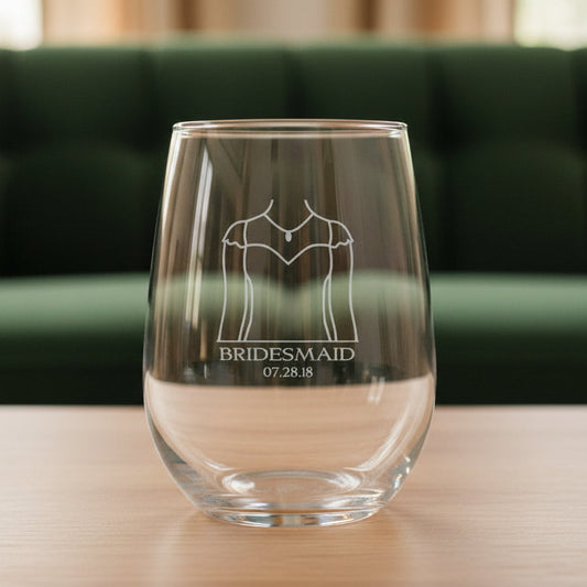 Clear glass with engraved design of a wedding dress and text with a green couch in the background
